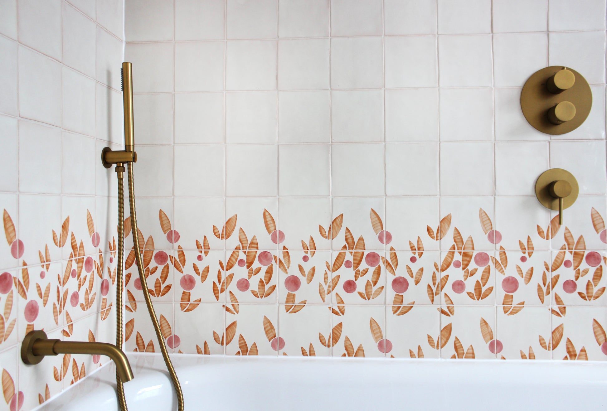 Cherry tile in Rust & Rose by Feild. Handmade and hand painted glazed terracotta tiles. Installed around a bath