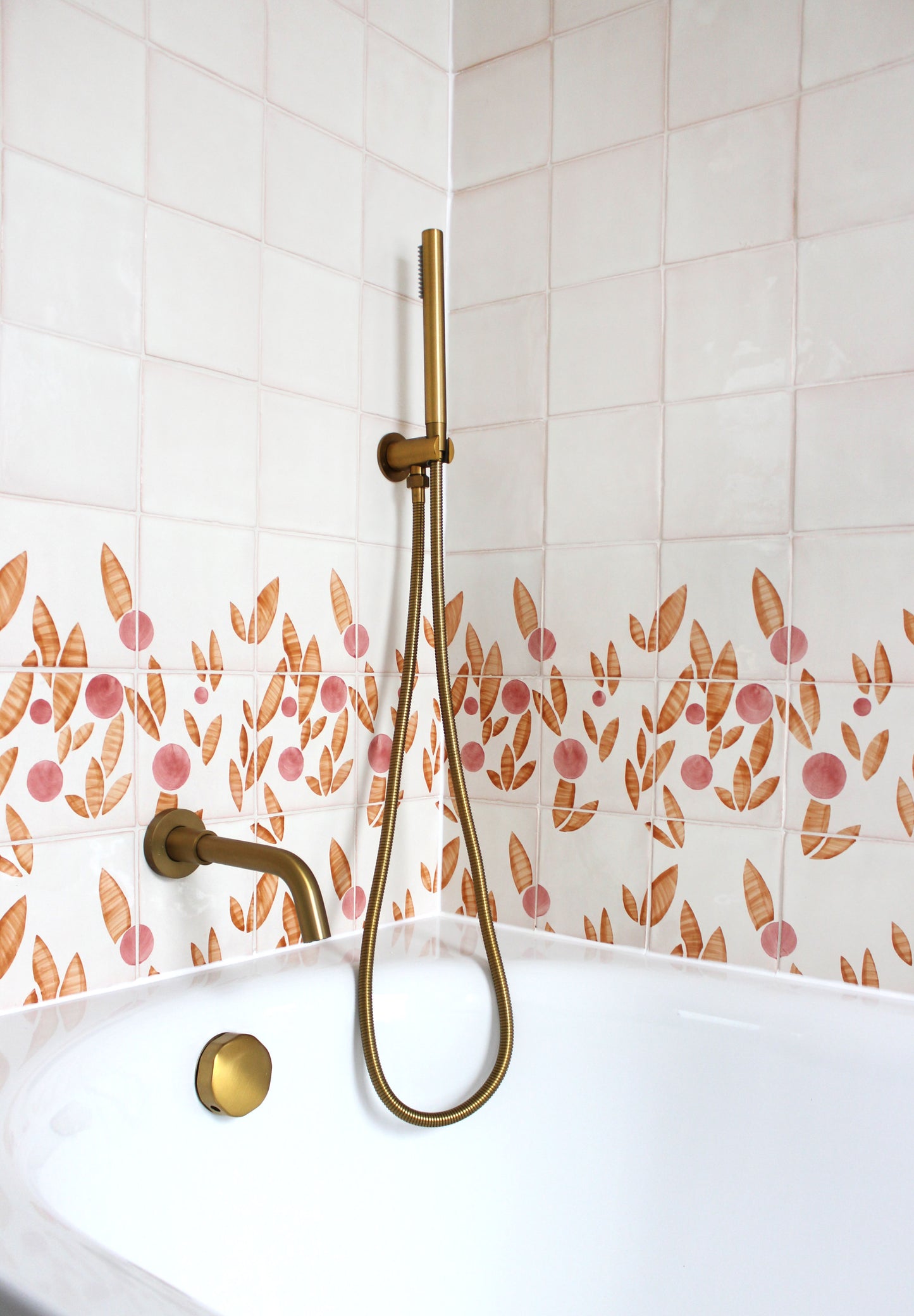 Cherry tile in Rust & Rose by Feild. Handmade and hand painted glazed terracotta tiles. Installed around a bath 